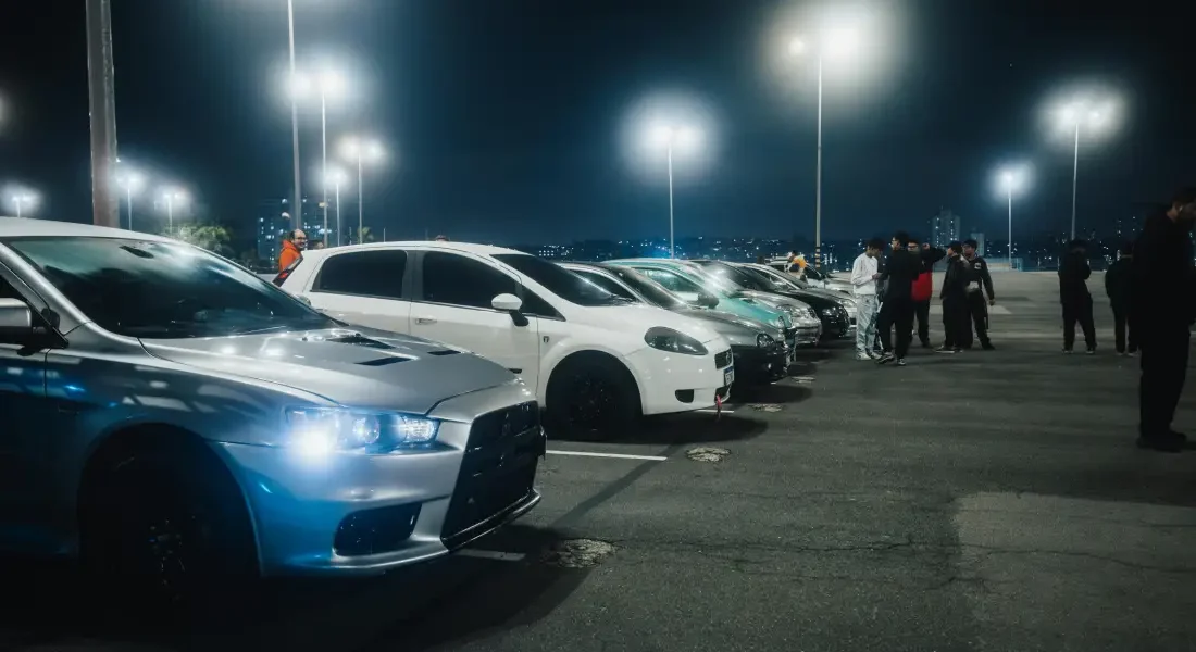 Rangée de voitures alignées sur un parking la nuit.