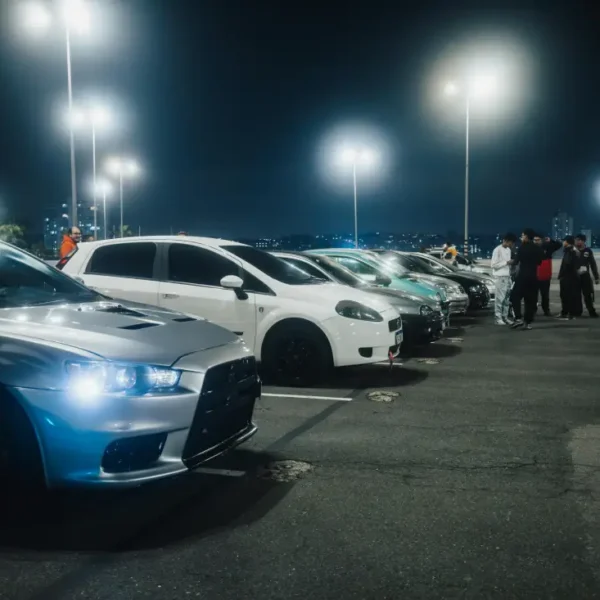 Rangée de voitures alignées sur un parking la nuit.
