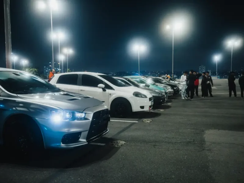 Rangée de voitures alignées sur un parking la nuit.