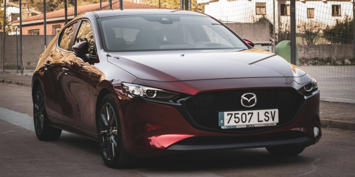 Mazda3 rouge garée de profil sur une route