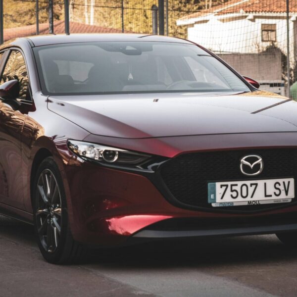 Mazda3 rouge garée de profil sur une route