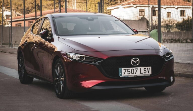 Mazda3 rouge garée de profil sur une route