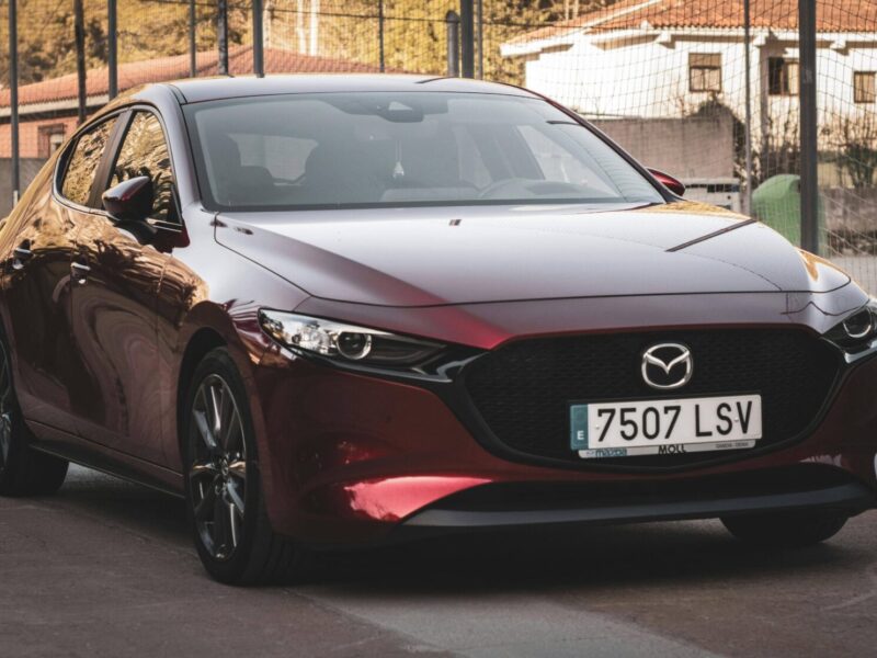 Mazda3 rouge garée de profil sur une route