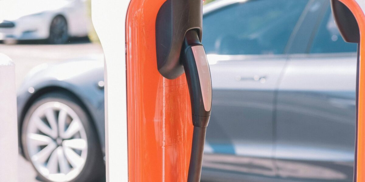 Borne de recharge Tesla avec câble rouge branché sur une voiture électrique