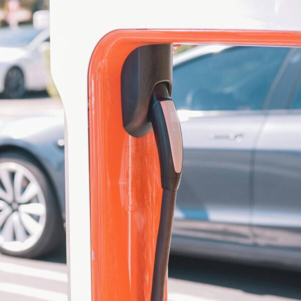 Borne de recharge Tesla avec câble rouge branché sur une voiture électrique