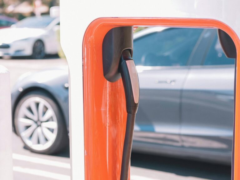 Borne de recharge Tesla avec câble rouge branché sur une voiture électrique