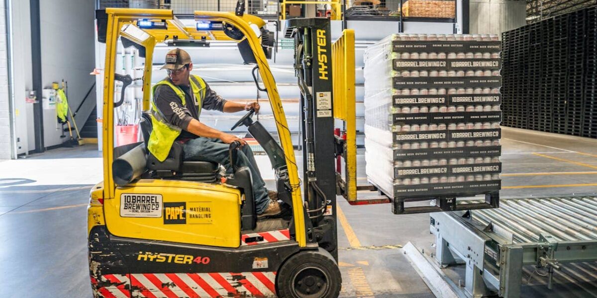 Employé logistique déplaçant des colis automobiles dans un entrepôt moderne